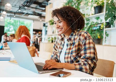 A Young Woman Engaged in Work on Her Laptop in a Contemporary and Stylish Cafe Setting 130615313