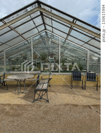 Chairs and tables for rest near greenhouse with plants in Copenhagen botanical garden. Favorite place of citizens and tourists in the center of Denmark capital. Chairs and tables for rest near greenhouse with plants in Copenhagen botanical garden. Favorite place of citizens and tourists in the center of Denmark capital. 130615994