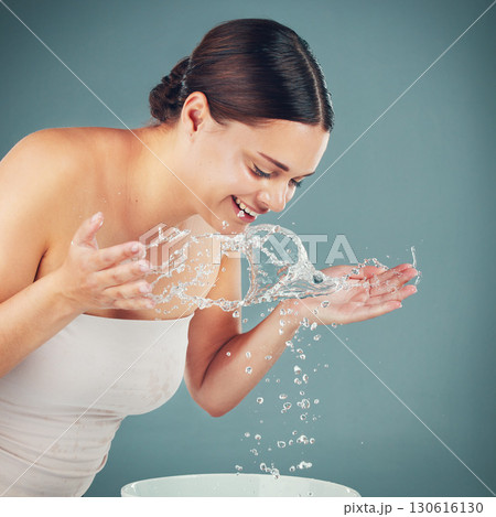 Water splash, woman and skincare while washing face for dermatology wellness on a studio background. Health and glow of a happy aesthetic model person cleaning skin or body for facial spa treatment 130616130