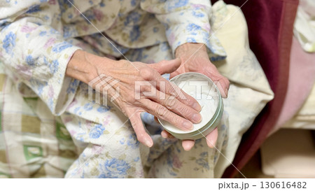 寝巻を着てハンドクリームを塗る高齢女性 130616482