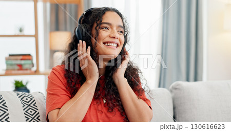Headphones, music and smile with woman on sofa for streaming service, audio app or connection. Online song album, radio subscription and relax with person in living room of home for sound and break 130616623