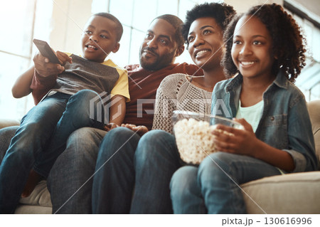 Black family watching tv on sofa for movie, film and cartoon together, bonding and quality time in living room. Popcorn, kids television show of people, mother and father with kids, on couch watching 130616996