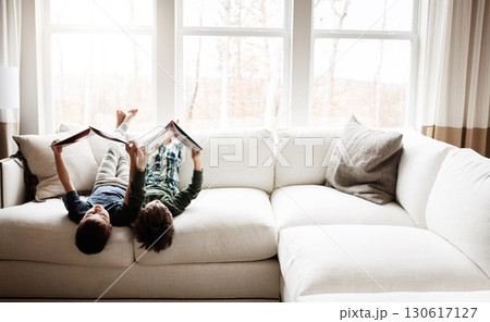 Fun children, bonding and reading books in education, learning or relax studying upside down on house living room or sofa. kids, storytelling and fantasy fairytale novel in creative home inspiration 130617127