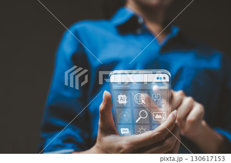 Person using transparent futuristic smartphone with artificial intelligence interface. Concept of advanced mobile technology, AI, innovation and digital transformation. Touchscreen display hologram. Person using transparent futuristic smartphone with artificial intelligence interface. Concept of advanced mobile technology, AI, innovation and digital transformation. Touchscreen display hologram. 130617153
