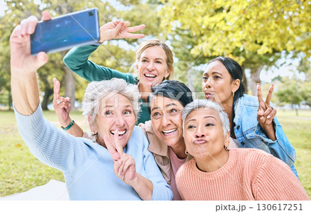Senior people, friends and phone for selfie at the park together with smile and peace sign in the outdoors. Happy group of silly elderly women smiling for photo looking at smartphone in nature Senior people, friends and phone for selfie at the park together with smile and peace sign in the outdoors. Happy group of silly elderly women smiling for photo looking at smartphone in nature 130617251