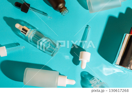 Glass cosmetic dropper bottles and pipettes on blue background. Skincare and beauty packaging concept. 130617268