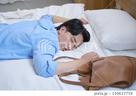 私服でベッドで寝る疲労した男性 130617759
