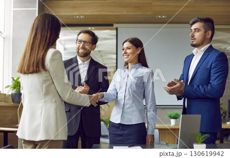 Business people in office making deal. Two women shaking hands celebrating business achievement. Business people in office making deal. Two women shaking hands celebrating business achievement. 130619942
