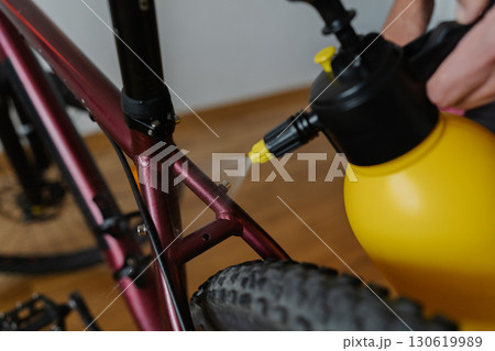 Bike mechanic spraying water on bicycle frame cleaning and maintaining in workshop, ensuring optimal performance for every ride, close-up. Concept of professional bicycle maintenance and service. 130619989