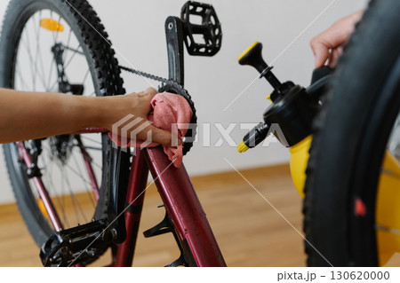 Close-up of two mechanics male cleaning mountain bike using spray bottle and cloth, wiping down frame and ensuring proper maintenance after trail riding, preserving cycling gear condition and service. 130620000