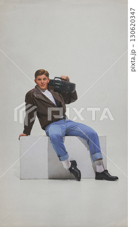 Man in casual retro outfit posing with boombox on shoulder smiling Man in casual retro outfit posing with boombox on shoulder smiling 130620347
