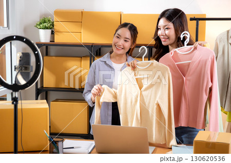 Two young asian woman live streaming online clothing store while showing clothing with smartphone. Two young asian woman live streaming online clothing store while showing clothing with smartphone. 130620536