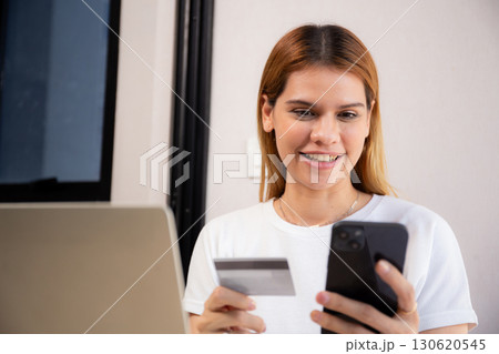 Happy young caucasian woman holding credit card or debit card paying with shopping online. Happy young caucasian woman holding credit card or debit card paying with shopping online. 130620545