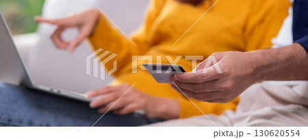 Closeup happy asian couple using laptop and credit card for online shopping together. Closeup happy asian couple using laptop and credit card for online shopping together. 130620554