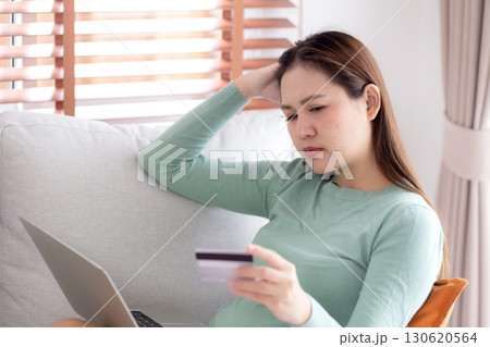 Young asian woman holding credit card or debit card with stress about loan and expense sitting. 130620564