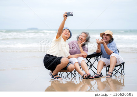 Happy group senior asian woman taking selfie on beach vacation, elderly friend smiling and enjoy. 130620595