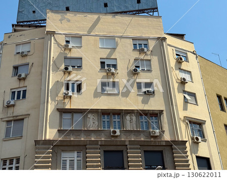 Residential building in Belgrade with decorated facade, relief carvings and multiple air conditioners on windows. Urban architecture, society, housing, cultural identity, daily life and historic 130622011
