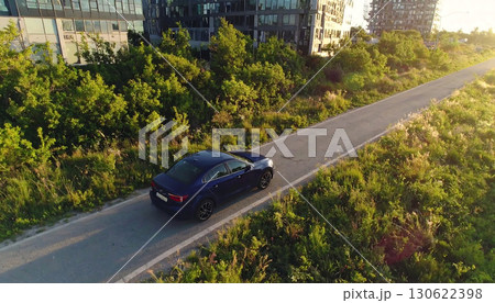 青いセダン車が緑豊かな郊外の道を静かに走る午後の風景「AI生成画像」 130622398