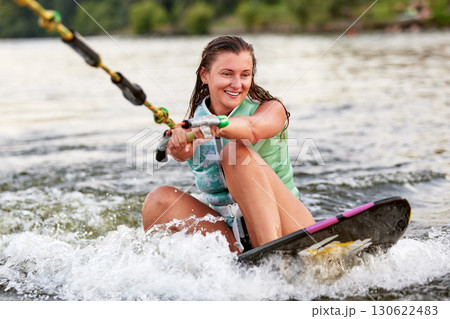 Young woman enjoying wakeboarding on a calm lake with joyful expression Young woman enjoying wakeboarding on a calm lake with joyful expression 130622483