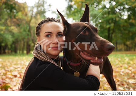 Woman Embracing a Brown Doberman Dog in an Autumn Park Setting Woman Embracing a Brown Doberman Dog in an Autumn Park Setting 130622531