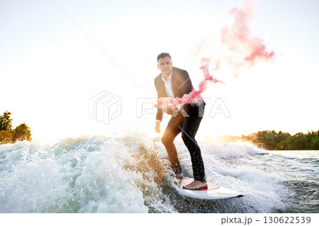 Man Surfing On A Wave Dressed In A Suit Holding Smoke Flare 130622539