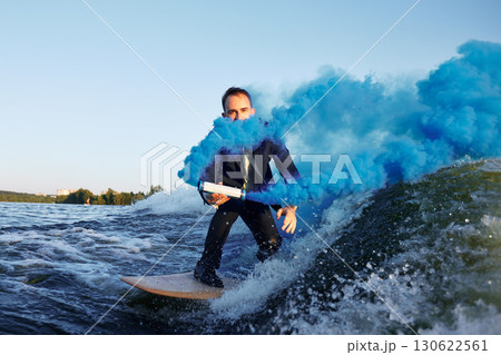 Man in Suit Surfs on Water With Vivid Blue Smoke Effects 130622561