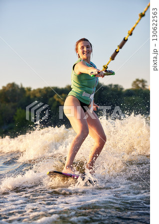 Young woman enjoying wakeboarding on a sunny summer day on the water 130622563