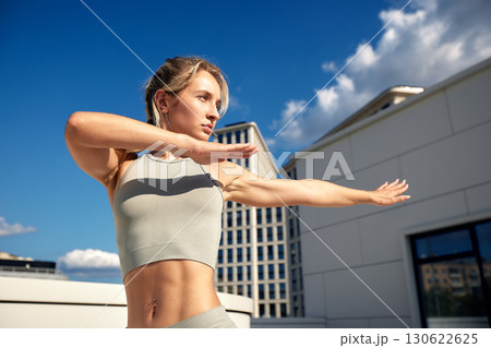 Fit woman practicing exercise in urban rooftop with blue skies and clouds Fit woman practicing exercise in urban rooftop with blue skies and clouds 130622625