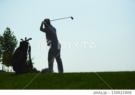 Golfer preparing swing silhouette with golf bag on green hill background Golfer preparing swing silhouette with golf bag on green hill background 130622866