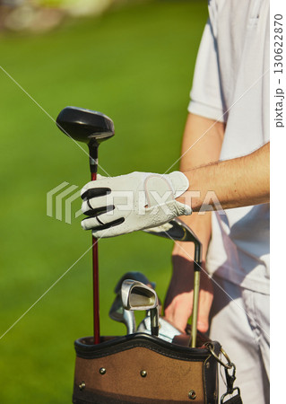 Golfer hand placing club back into golf bag on green field Golfer hand placing club back into golf bag on green field 130622870