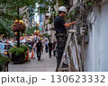 Electrician in hardhat on stepladder repairing electricity on busy evening city street with glowing lamps and many people 130623332