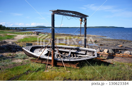 Weathered wooden boat on coastal landscape with blue sky by White Sea near Belomorsk in Karelia, nature of Russia Weathered wooden boat on coastal landscape with blue sky by White Sea near Belomorsk in Karelia, nature of Russia 130623384