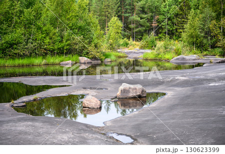 Scenic forest with rocks, water and lush greenery in tranquil natural setting, landscape of Karelia, Russia Scenic forest with rocks, water and lush greenery in tranquil natural setting, landscape of Karelia, Russia 130623399