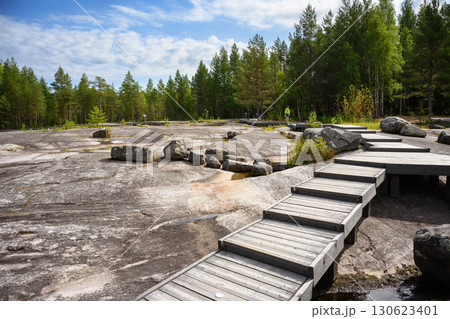 Scenic wooden pathway through rocky terrain and dense forest in Zalavruga, area with prehistoric art in Karelia, Russia Scenic wooden pathway through rocky terrain and dense forest in Zalavruga, area with prehistoric art in Karelia, Russia 130623401