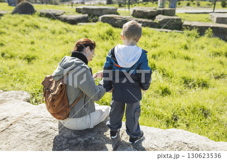 Mother and son exploring nature, observing wildlife on rock 130623536