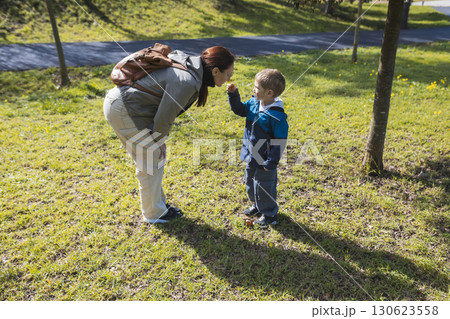 Mother and son smelling a flower in the park during springtime Mother and son smelling a flower in the park during springtime 130623558