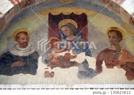 Virgin Mary with baby Jesus and Saints, lunette over the entrance door to the Sant Anastasio church in Lucca, Tuscany, Italy 130623612