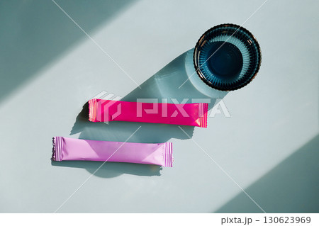 Two colorful sachets and blue glass with water on blue background. Two colorful sachets and blue glass with water on blue background. 130623969