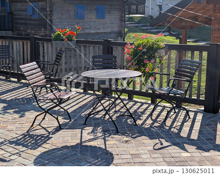 Round table with black chairs on stone square near traditional buildings. Outdoor cafe in Drvengrad. 130625011