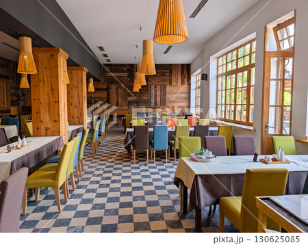 Dining hall with colorful seating and rustic decor. Social atmosphere, hospitality, rural tourism and wooden architecture. Dining hall with colorful seating and rustic decor. Social atmosphere, hospitality, rural tourism and wooden architecture. 130625085