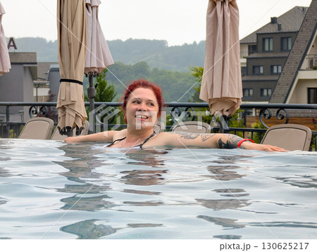 Smiling woman enjoying relaxation in pool. Holiday, leisure, and calm travel experience. 130625217