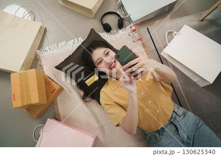 Online shopping. Cheerful woman lying on the floor with shopping bags and phone. Online shopping. Cheerful woman lying on the floor with shopping bags and phone. 130625340