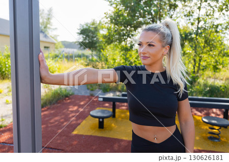 Woman stretching outdoors at a fitness park under sunny weather 130626181