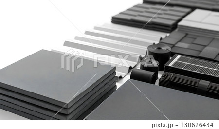 Assorted construction materials arranged neatly in rows, featuring sheets, tiles, and rolled materials in shades of black, gray, and white. No text is present 130626434