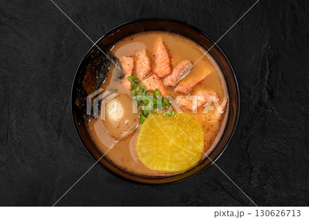 Salmon miso soup with egg, pickled radish, seaweed and green onions in bowl on dark background 130626713