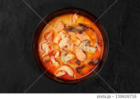Tom yam soup with salmon, shrimp, and mushrooms in black bowl Tom yam soup with salmon, shrimp, and mushrooms in black bowl 130626716