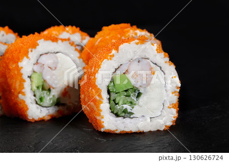 California uramaki sushi rolls with flying fish roe, shrimp, avocado and cucumber lying on a black slate plate California uramaki sushi rolls with flying fish roe, shrimp, avocado and cucumber lying on a black slate plate 130626724