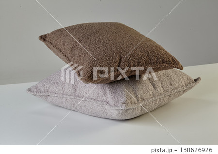 Two fluffy square cushions resting on white surface 130626926