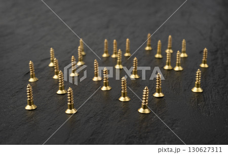 Yellow metal screws pile. Gold bolts close up 130627311