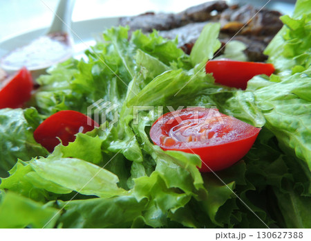 Roasted beef on a pillow of fresh salad leaves and cherry tomatoes closeup stock photo 130627388